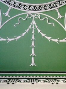 White plaster drops, bows and swirls on a grand curved ceiling which is painted emerald green for a true Georgian style interior.
